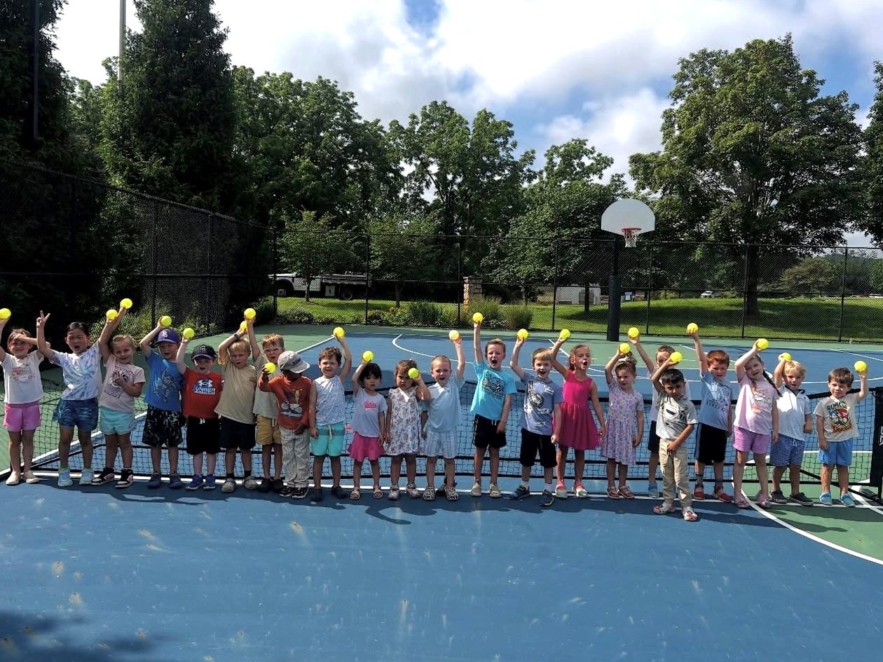 Ready Set Rackets toddlers holding up balls at the net