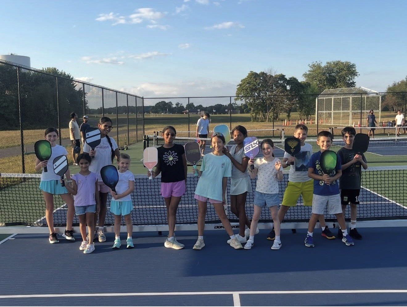 Junior campers holding paddles on the pickleball court at summer camp