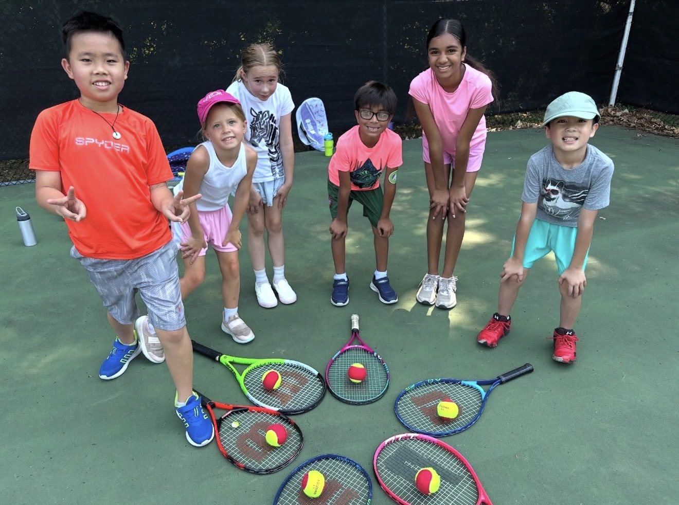 Young campers gathered around their racquets at a Universal Rackets tennis camp
