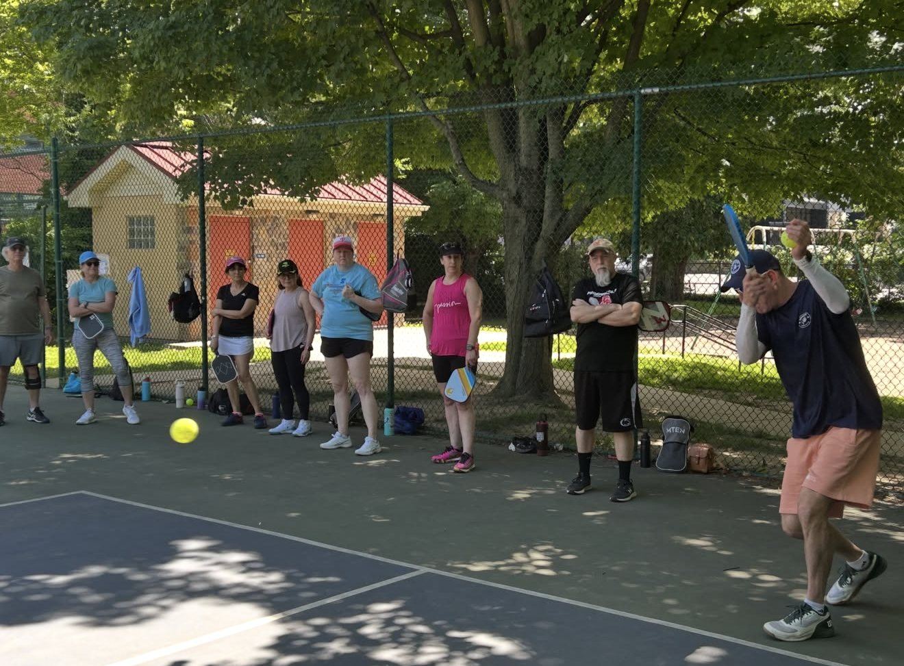 A Universal Rackets coach demonstrating a shot while a community clinic looks on
